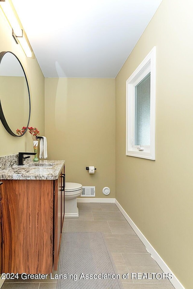 bathroom featuring vanity, tile patterned flooring, and toilet