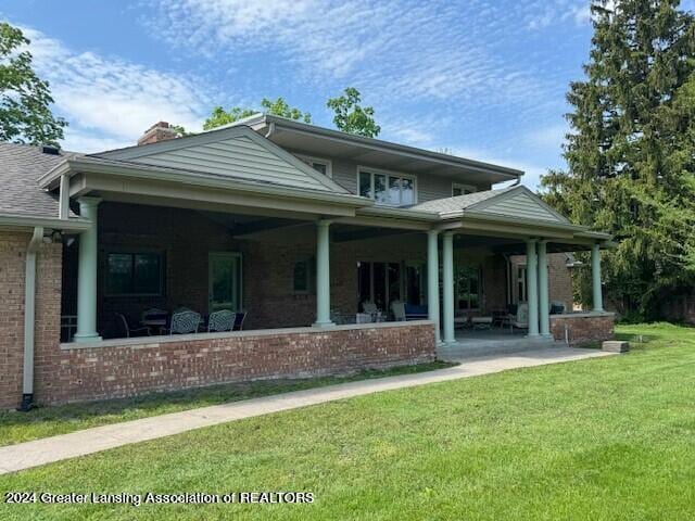 back of house featuring a lawn and covered porch