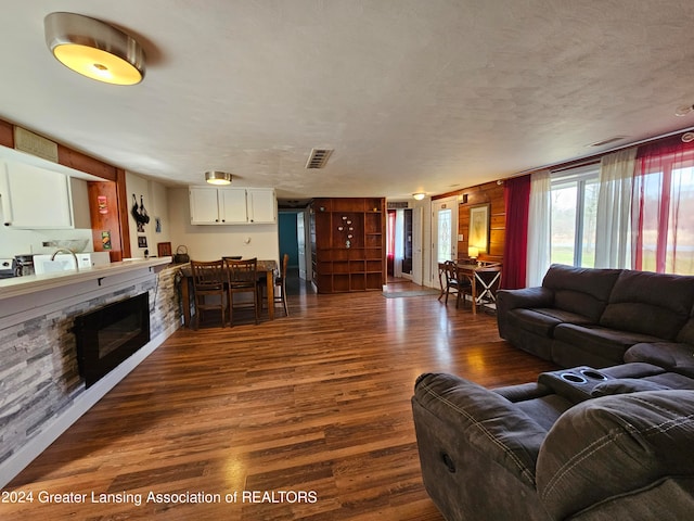 living room with a textured ceiling, a fireplace, and dark hardwood / wood-style flooring