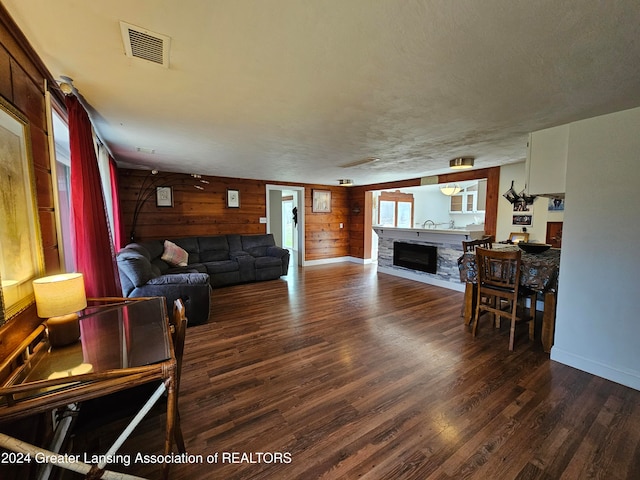 living room featuring a textured ceiling, wood walls, and dark hardwood / wood-style floors