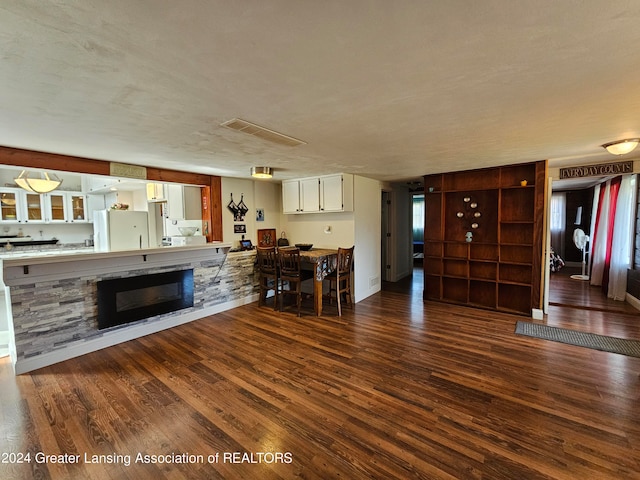 unfurnished living room featuring a textured ceiling, a stone fireplace, and dark hardwood / wood-style floors