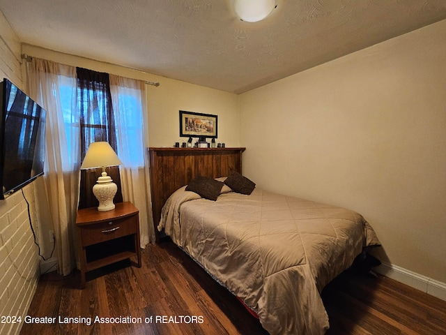 bedroom with a textured ceiling and dark hardwood / wood-style floors