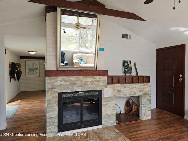 unfurnished living room featuring ceiling fan, brick wall, hardwood / wood-style flooring, lofted ceiling with beams, and a fireplace