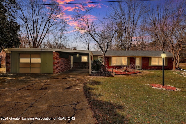 single story home featuring a garage, a lawn, and a carport