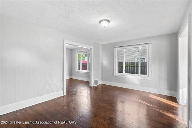 unfurnished room with a textured ceiling and dark hardwood / wood-style flooring