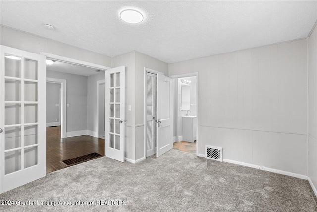 spare room with carpet floors, a textured ceiling, and french doors