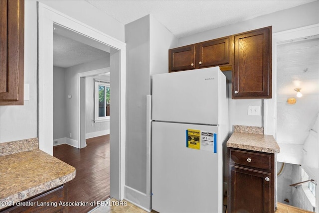 kitchen with a textured ceiling, dark hardwood / wood-style flooring, and white fridge