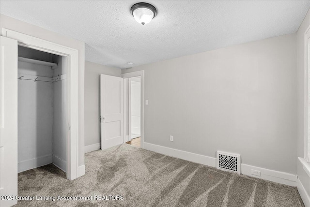 unfurnished bedroom with a textured ceiling, carpet flooring, and a closet