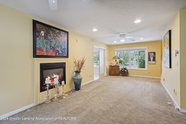 unfurnished living room with a textured ceiling, ceiling fan, and light colored carpet