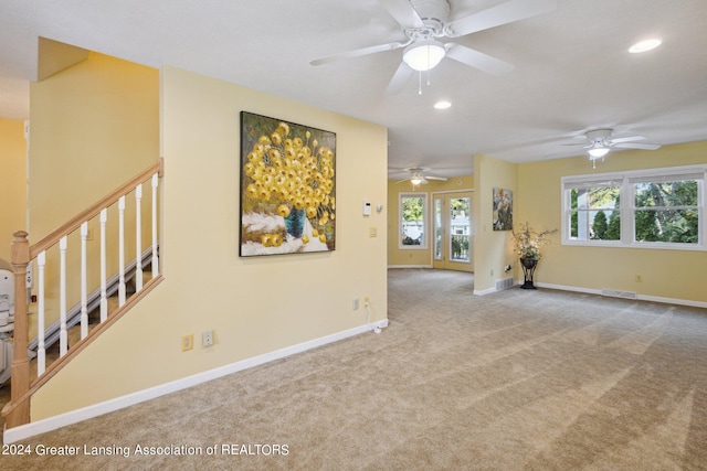 carpeted spare room featuring ceiling fan and plenty of natural light