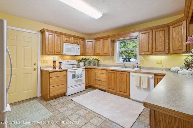 kitchen featuring a textured ceiling, sink, and white appliances