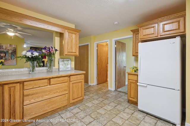 kitchen with ceiling fan, white refrigerator, and a textured ceiling