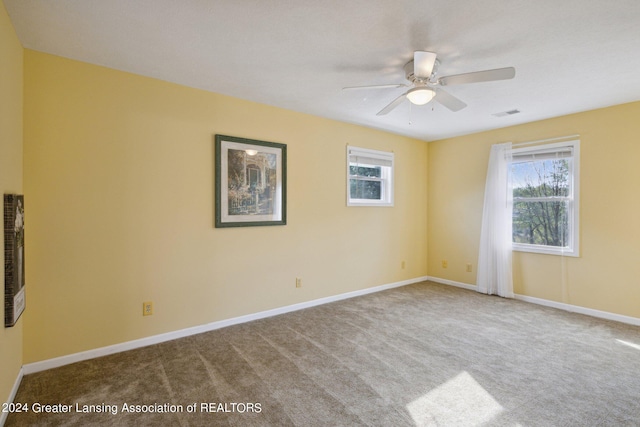 carpeted empty room featuring ceiling fan and a wealth of natural light