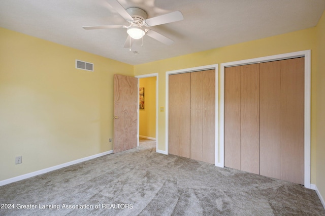 unfurnished bedroom featuring ceiling fan, two closets, and light carpet