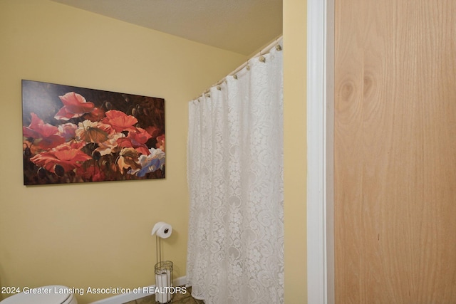 bathroom with curtained shower and toilet