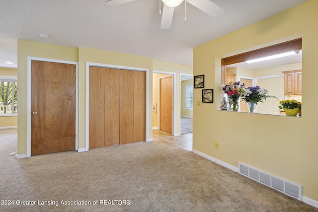 carpeted bedroom featuring ceiling fan and two closets