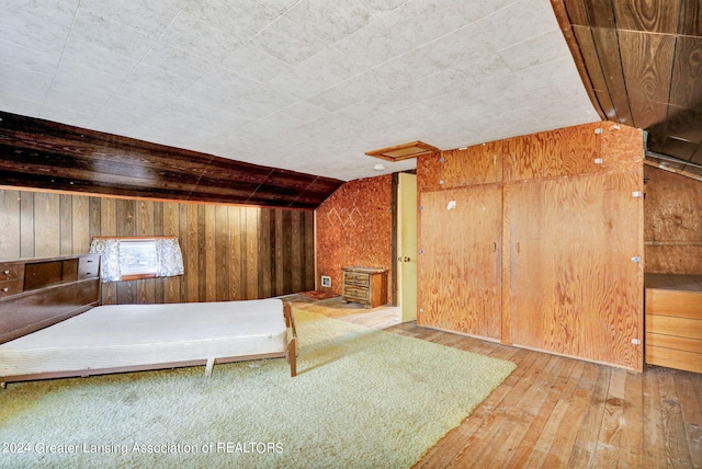 interior space with wood-type flooring, wooden walls, and vaulted ceiling