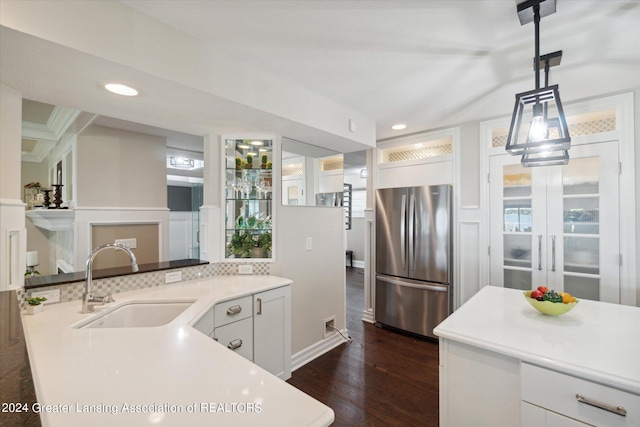 kitchen featuring pendant lighting, dark wood-type flooring, sink, white cabinetry, and stainless steel refrigerator