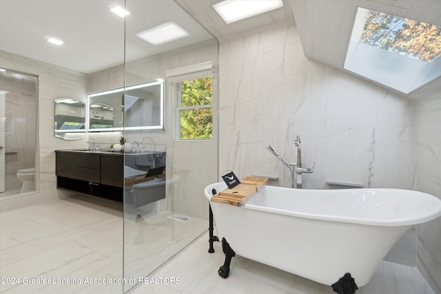 bathroom with vanity, tile walls, toilet, and a bath