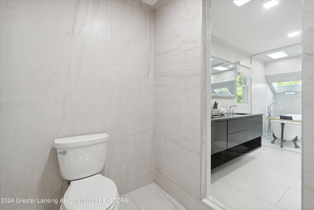 bathroom with tile walls, vanity, and toilet