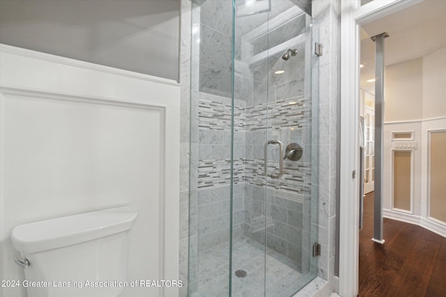 bathroom featuring hardwood / wood-style flooring, an enclosed shower, and toilet