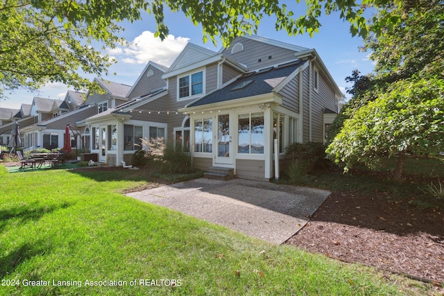 view of front of house featuring a sunroom and a front lawn