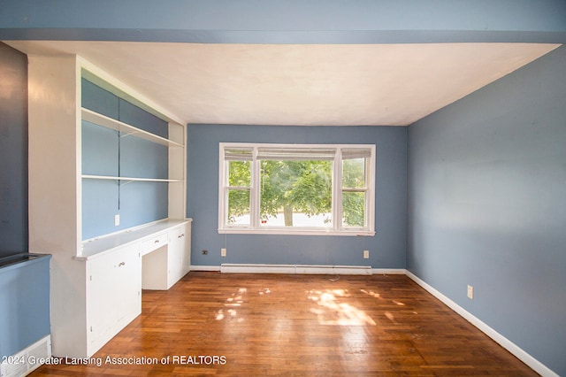 empty room featuring built in desk and dark wood-type flooring