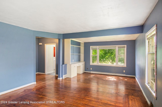 spare room featuring a baseboard heating unit and dark wood-type flooring