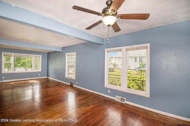 spare room with ceiling fan, beamed ceiling, dark hardwood / wood-style floors, and a healthy amount of sunlight