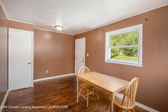 dining area featuring wood walls and dark wood-type flooring