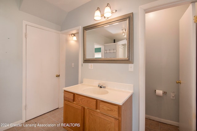 bathroom featuring tile patterned flooring, vaulted ceiling, and vanity