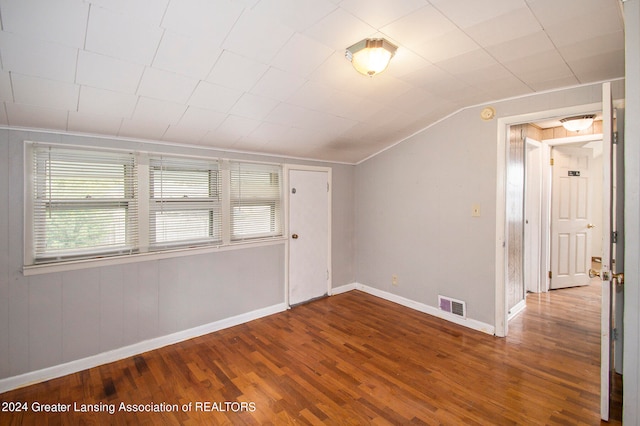 spare room with wood-type flooring and lofted ceiling