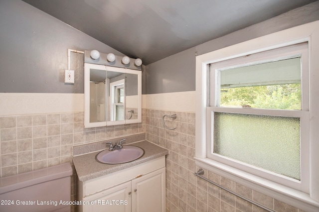 bathroom featuring vanity, tile walls, and lofted ceiling