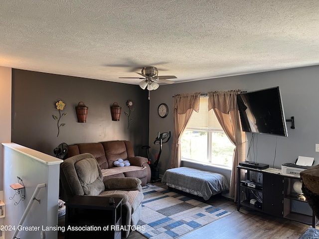 living room featuring ceiling fan, a textured ceiling, and dark hardwood / wood-style flooring