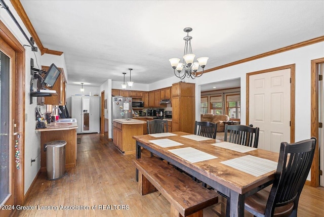 dining room with a notable chandelier, crown molding, light hardwood / wood-style floors, and sink