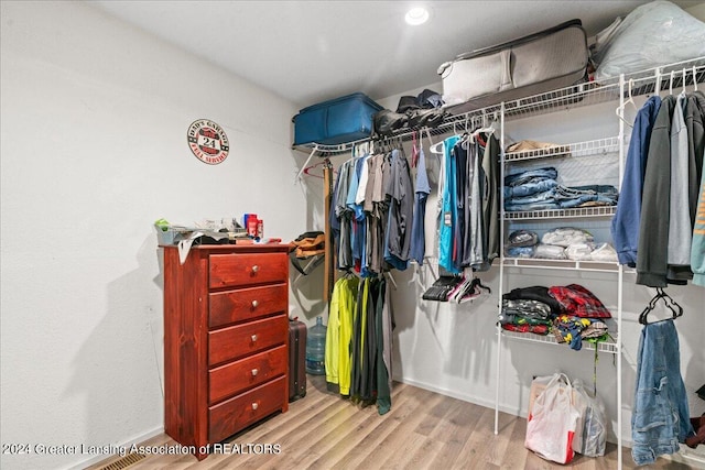 walk in closet with light hardwood / wood-style flooring