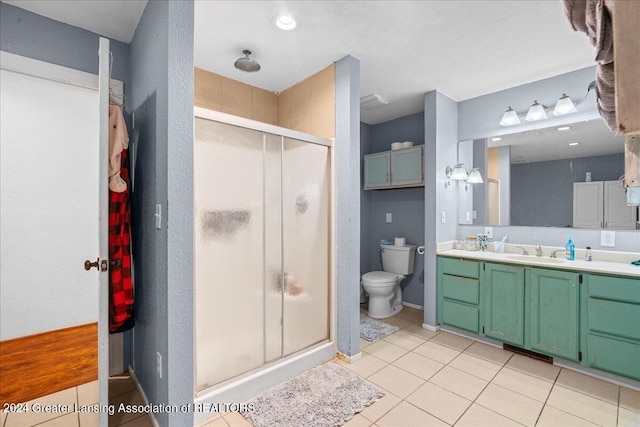 bathroom with vanity, toilet, a shower with door, and tile patterned floors