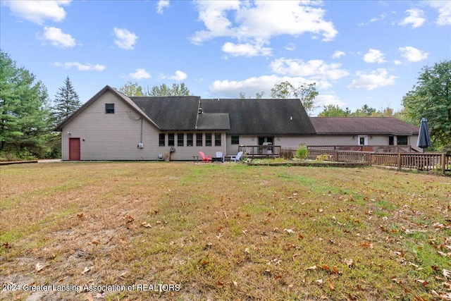 rear view of property featuring a lawn and a deck