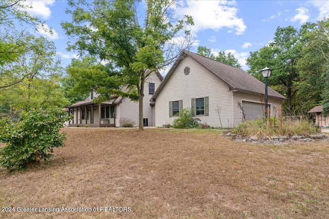 view of side of home featuring a yard, covered porch, and a garage