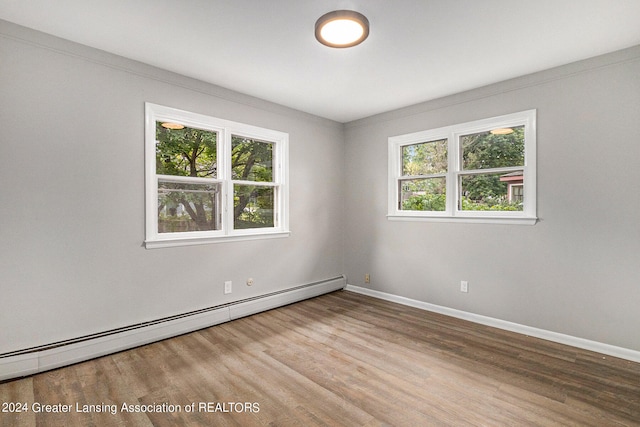 spare room with a baseboard radiator, wood-type flooring, and a healthy amount of sunlight