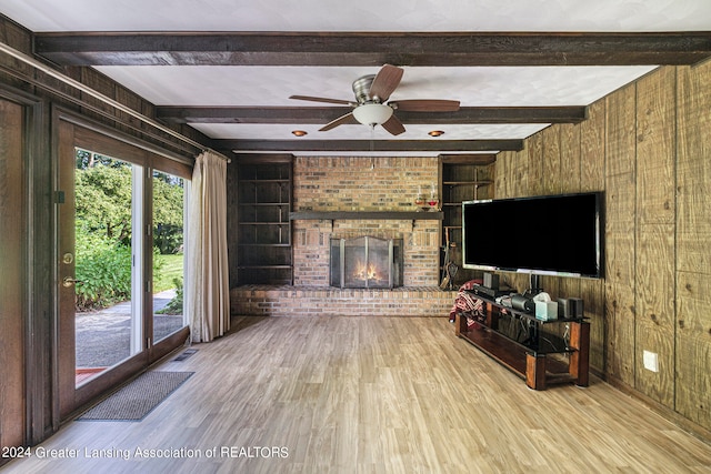 living room featuring beam ceiling, wood walls, hardwood / wood-style floors, and ceiling fan