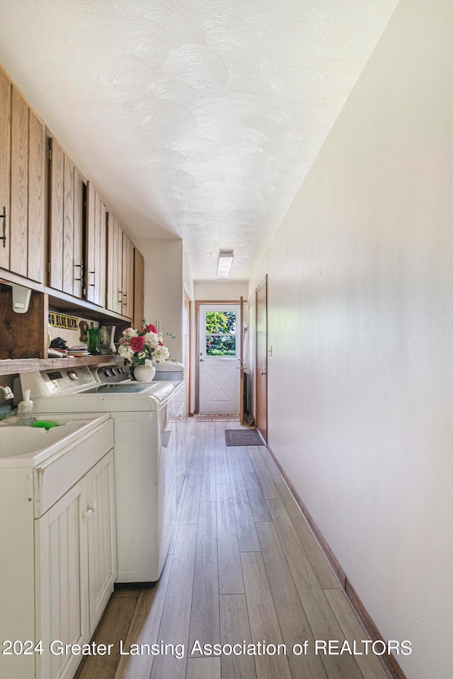 washroom featuring cabinets, light hardwood / wood-style floors, and independent washer and dryer