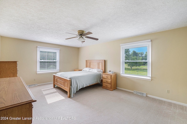 carpeted bedroom featuring ceiling fan and a textured ceiling