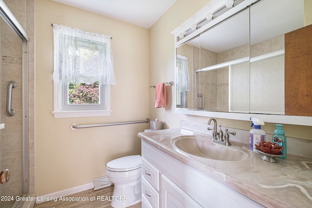 bathroom with wood-type flooring, vanity, toilet, and an enclosed shower