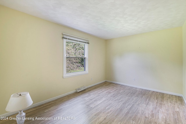 unfurnished room featuring light hardwood / wood-style flooring and a textured ceiling