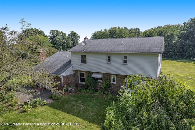 back of property with central AC and a yard