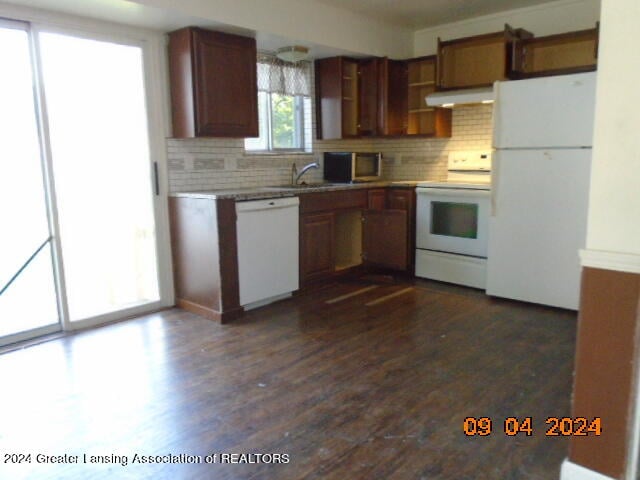 kitchen with sink, white appliances, dark hardwood / wood-style floors, range hood, and decorative backsplash