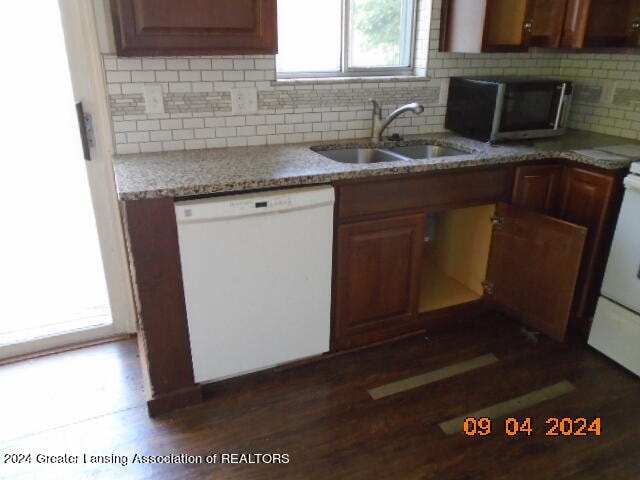 kitchen with decorative backsplash, light stone countertops, white dishwasher, dark hardwood / wood-style flooring, and sink