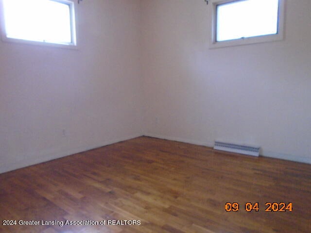 unfurnished room with plenty of natural light and dark hardwood / wood-style flooring