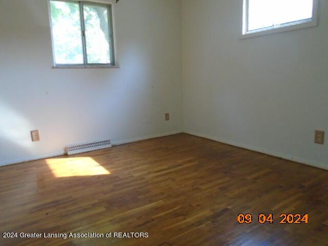 empty room with dark hardwood / wood-style flooring and plenty of natural light